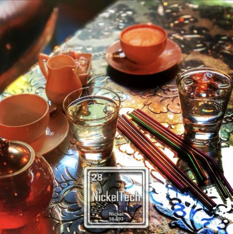 Tea and glass cups on a decorative table with colourful straws.