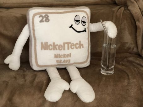 A plush representation of nickel, smiling and holding a glass.
