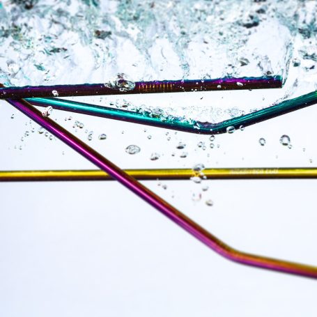 Colourful metal straws partially submerged in bubbling water.